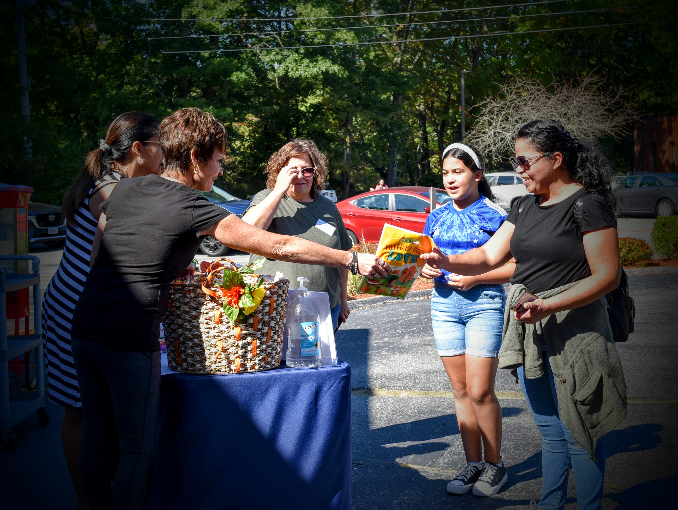 Community outreach food distribution event with volunteers serving families from outdoor table with food baskets